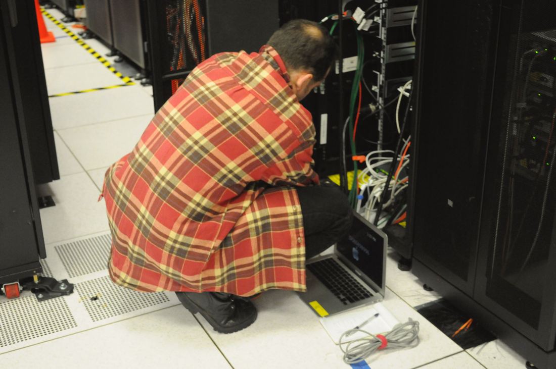 A technician working on a laptop beside a server rack